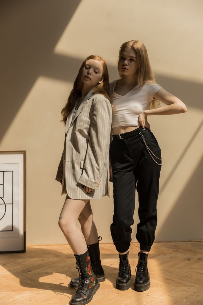 contact-img Two stylish caucasian women in trendy outfits posing indoors with creative shadows.